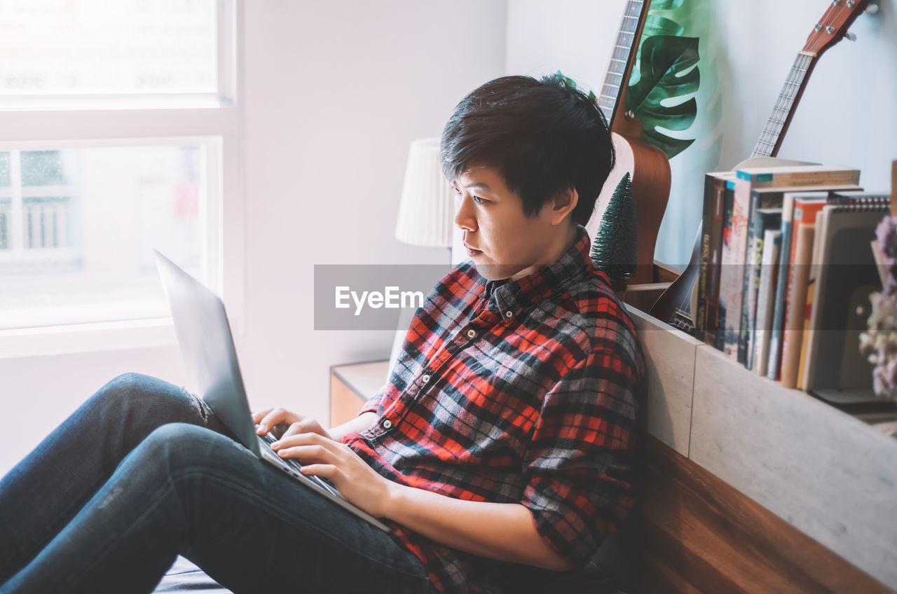 Side view of man using laptop while sitting at home