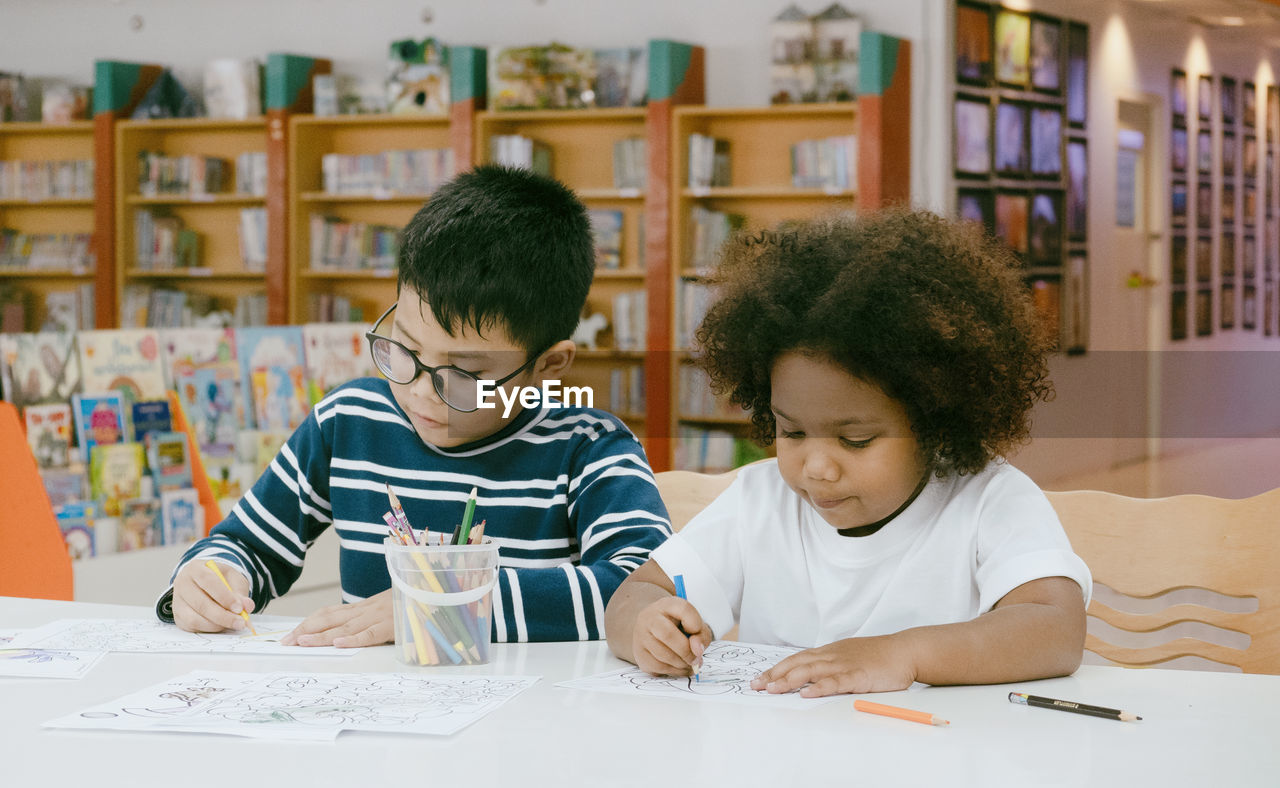 Friends drawing in paper at library