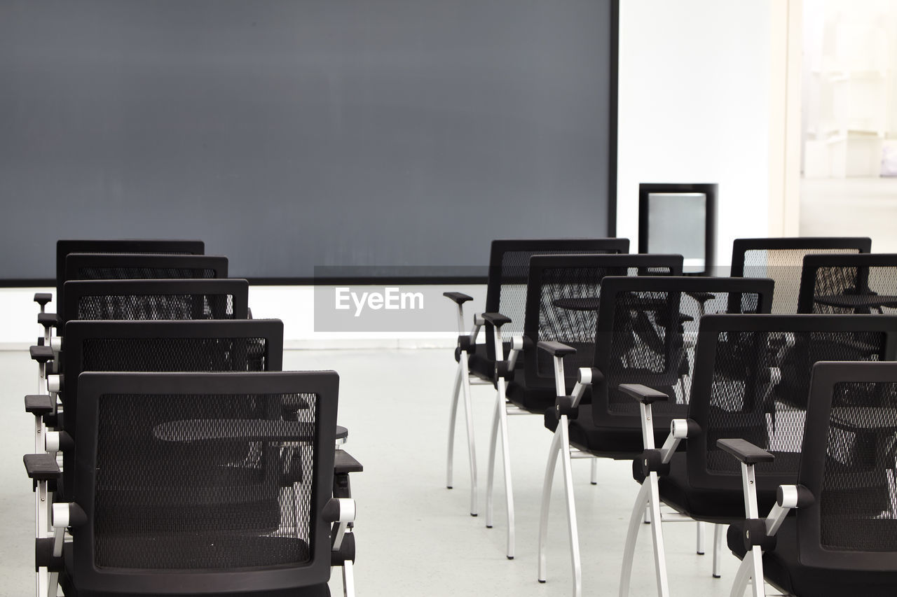 Empty black chairs arranged in classroom