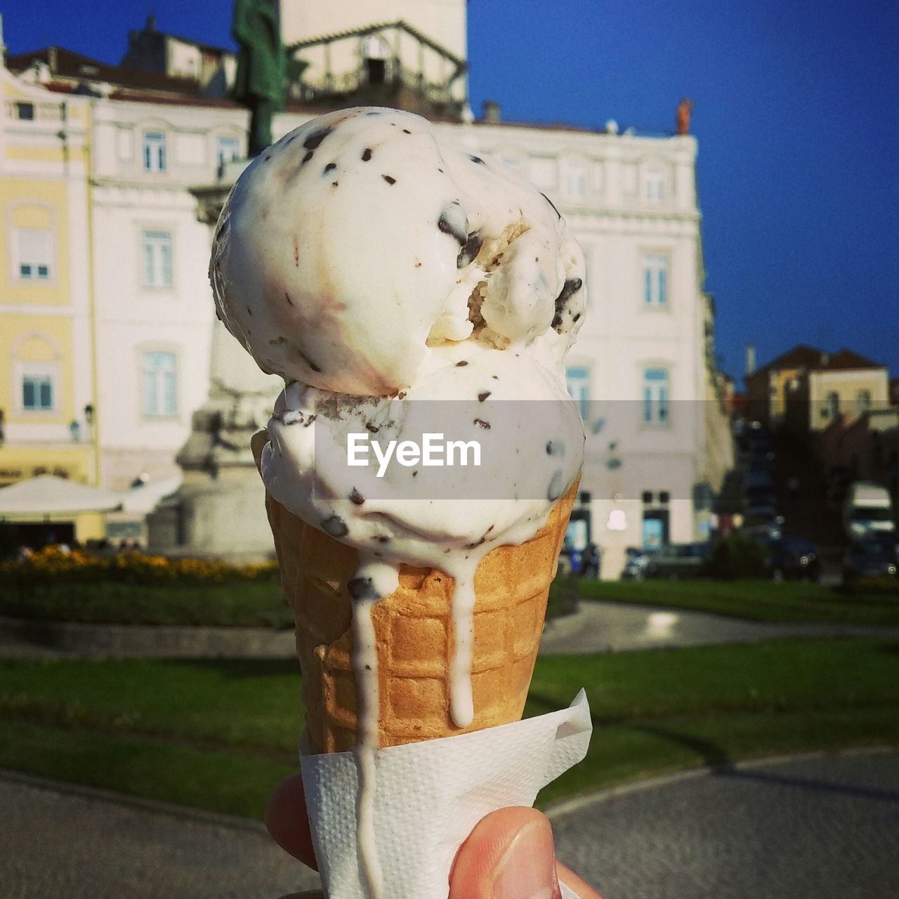 Cropped image of hand holding ice cream against building