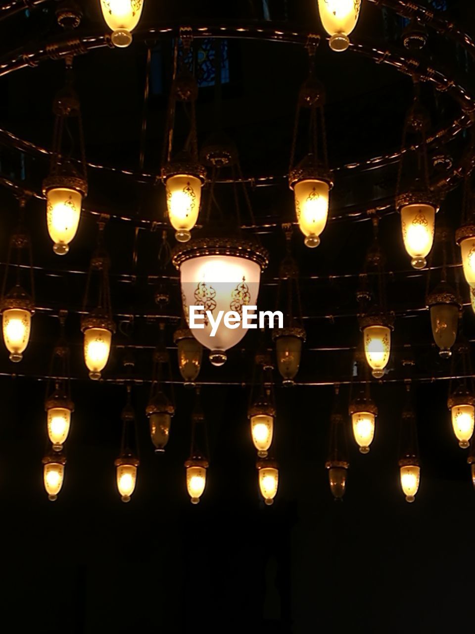 LOW ANGLE VIEW OF ILLUMINATED LANTERNS HANGING IN ROW