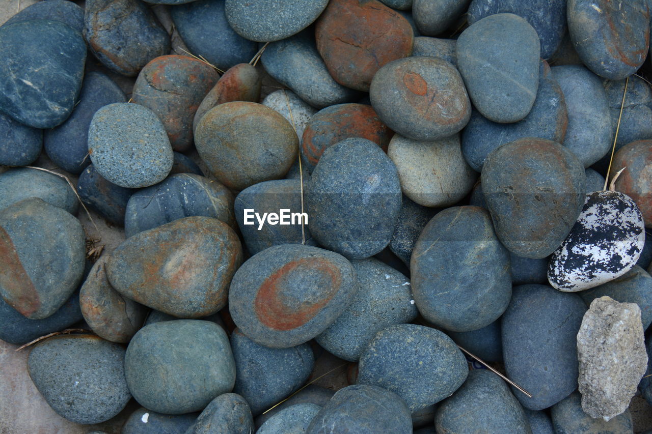 FULL FRAME SHOT OF PEBBLES ON ROCKS