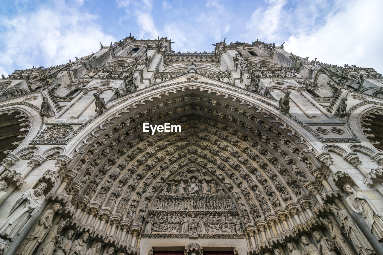 Low angle view of cathedral building in amiens against cloudy sky