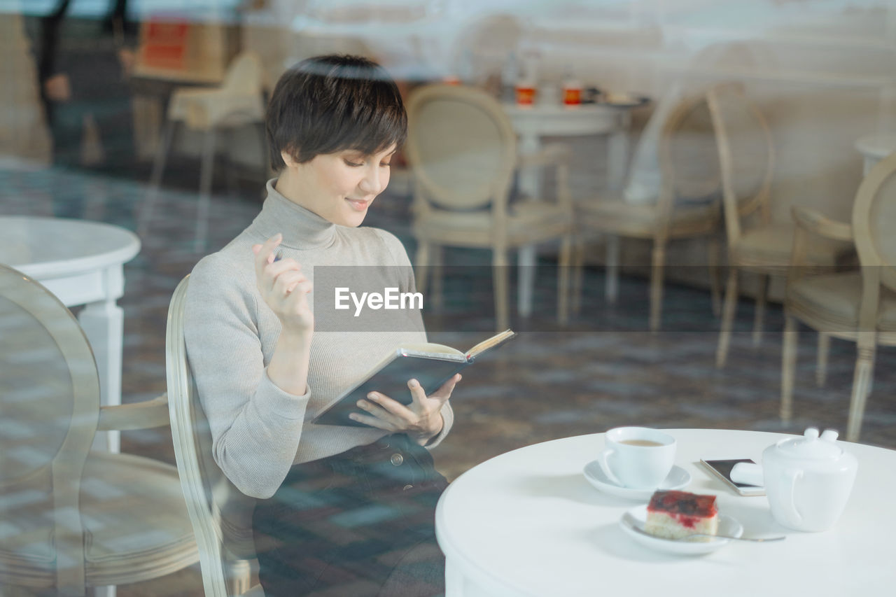 Woman reading diary while sitting at cafe