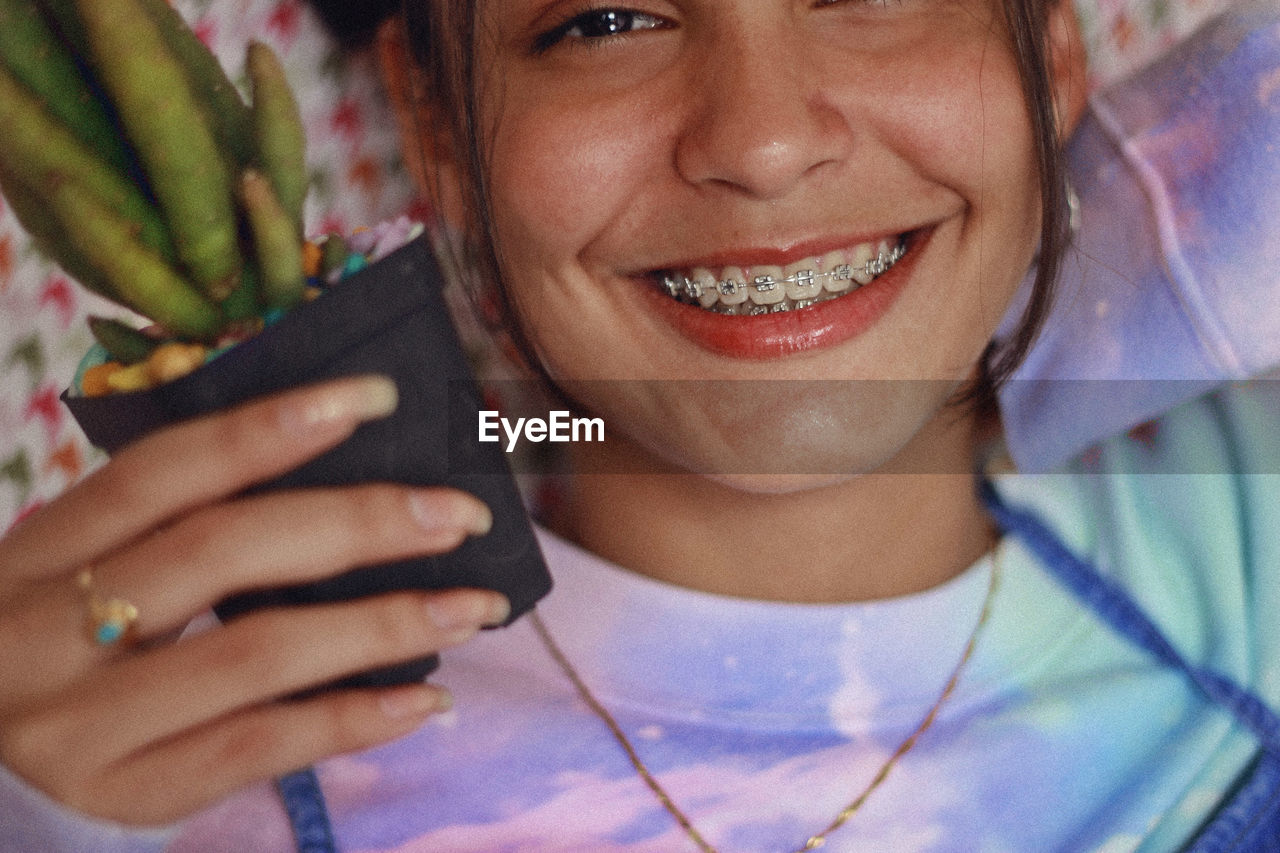 Close-up portrait of teenage girl holding potted plant