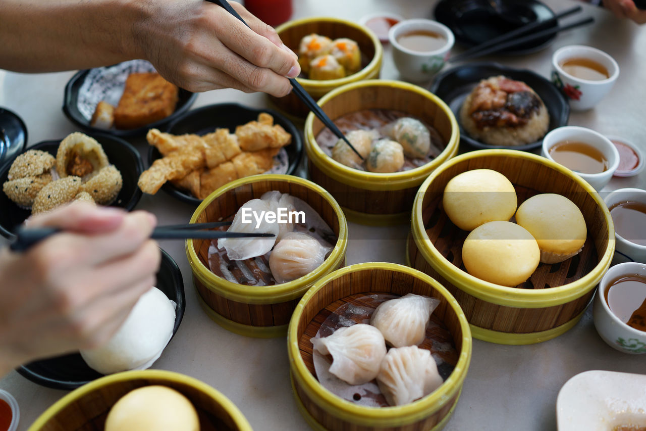 Cropped hands having dim sums at table