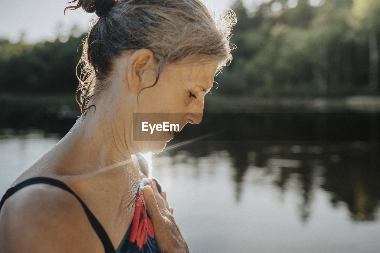 Senior woman is drying herself after swimming in lake