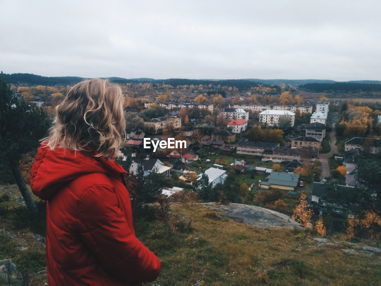 Side view of woman looking at cityscape against sky during autumn