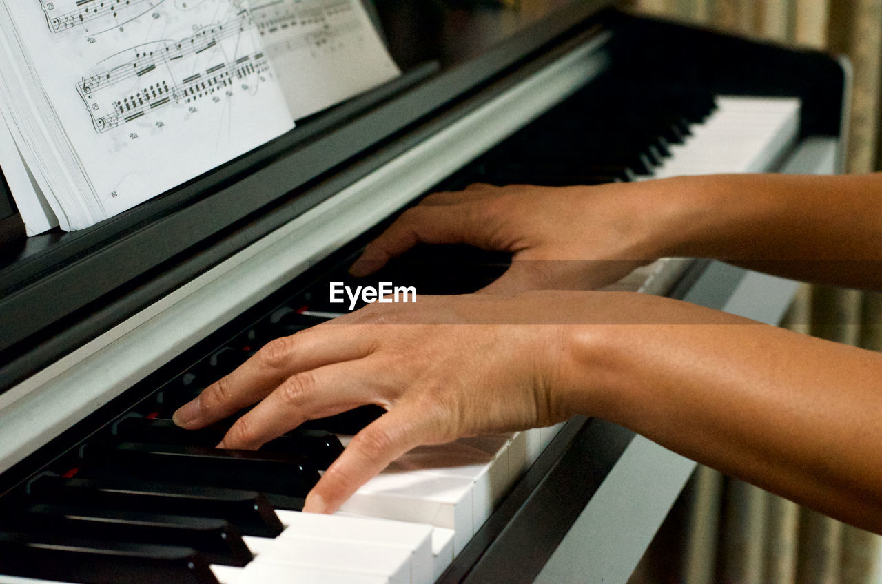 Cropped hands of woman playing piano