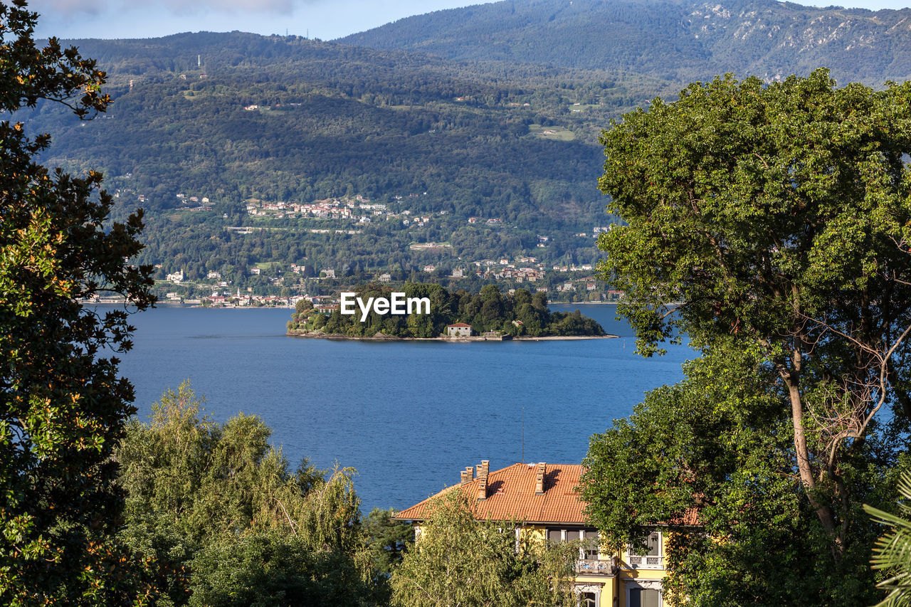 HIGH ANGLE VIEW OF LAKE AND TREES AGAINST MOUNTAINS