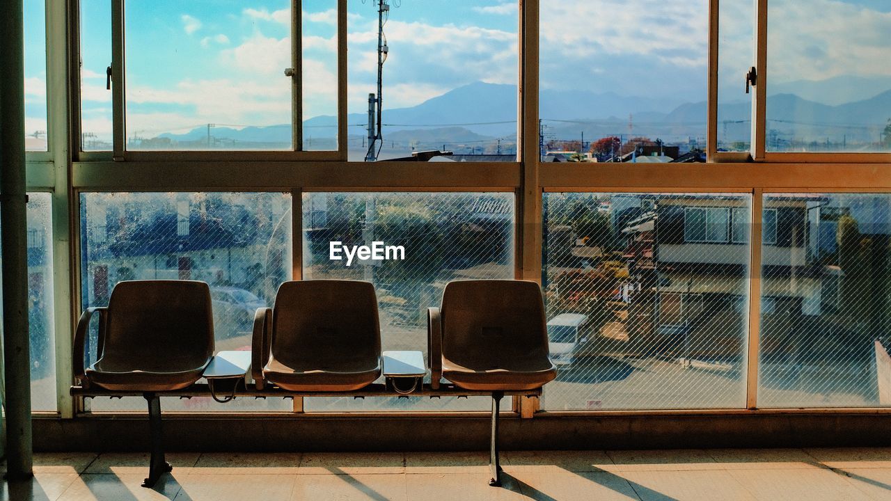 Empty chairs near window at train station
