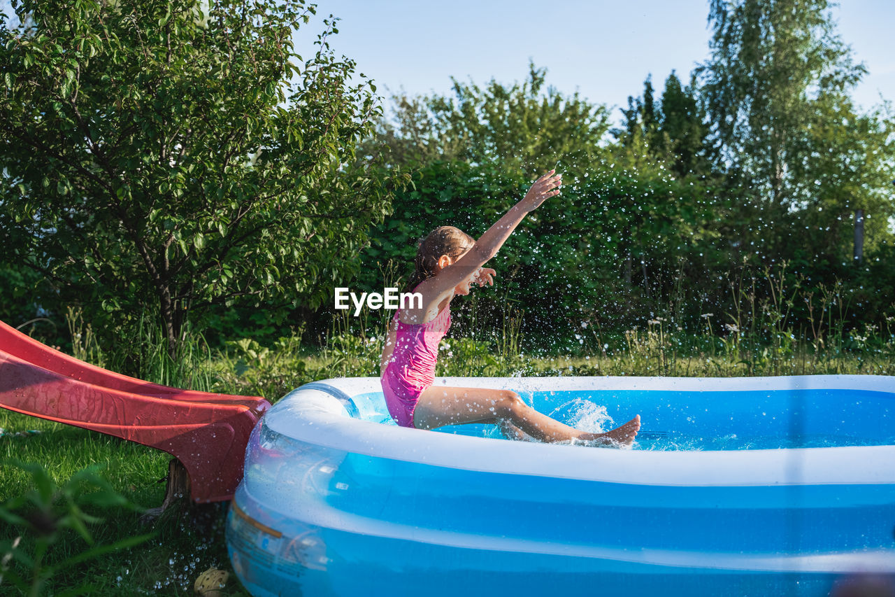 GIRL IN SWIMMING POOL BY TREES