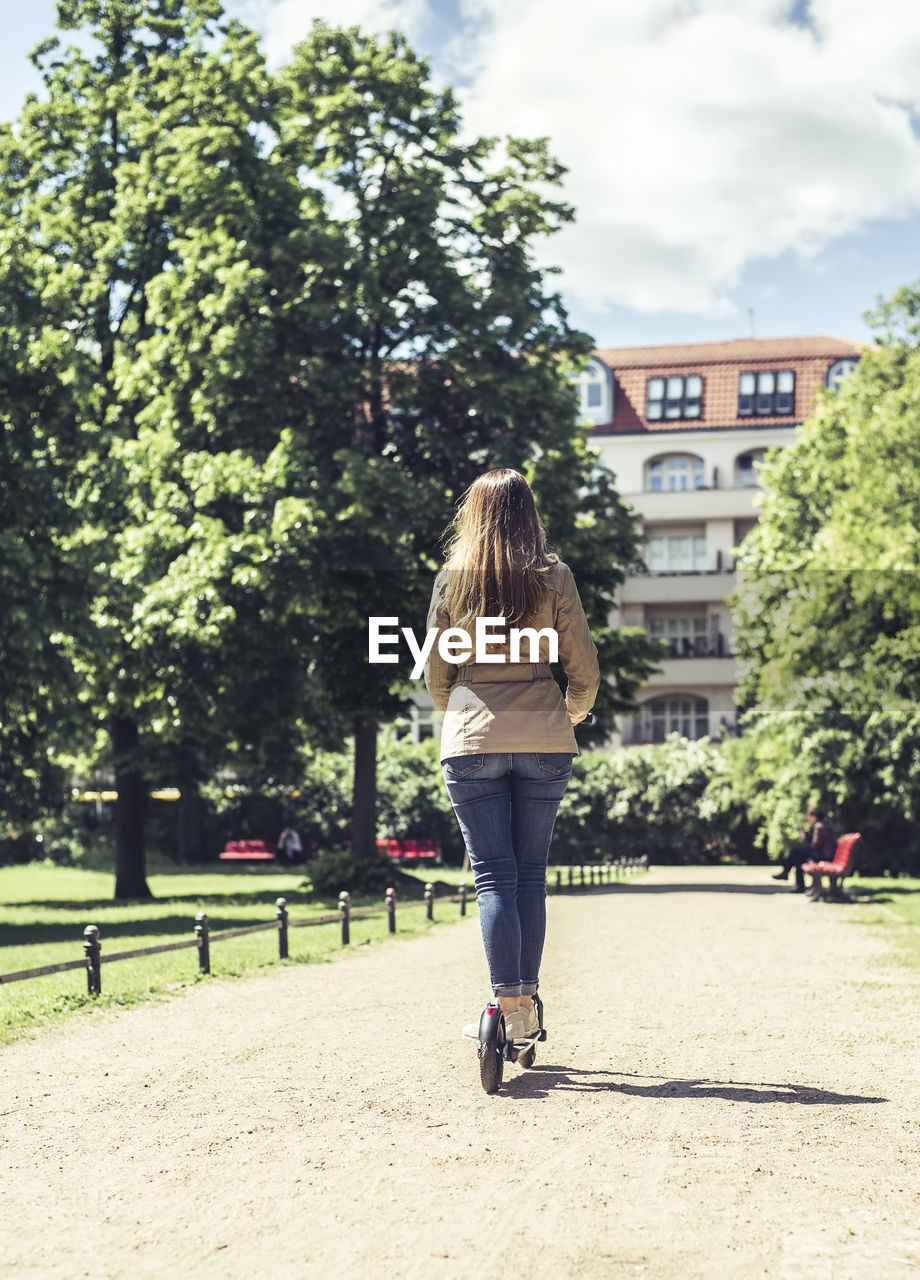 FULL LENGTH REAR VIEW OF WOMAN WALKING ON ROAD