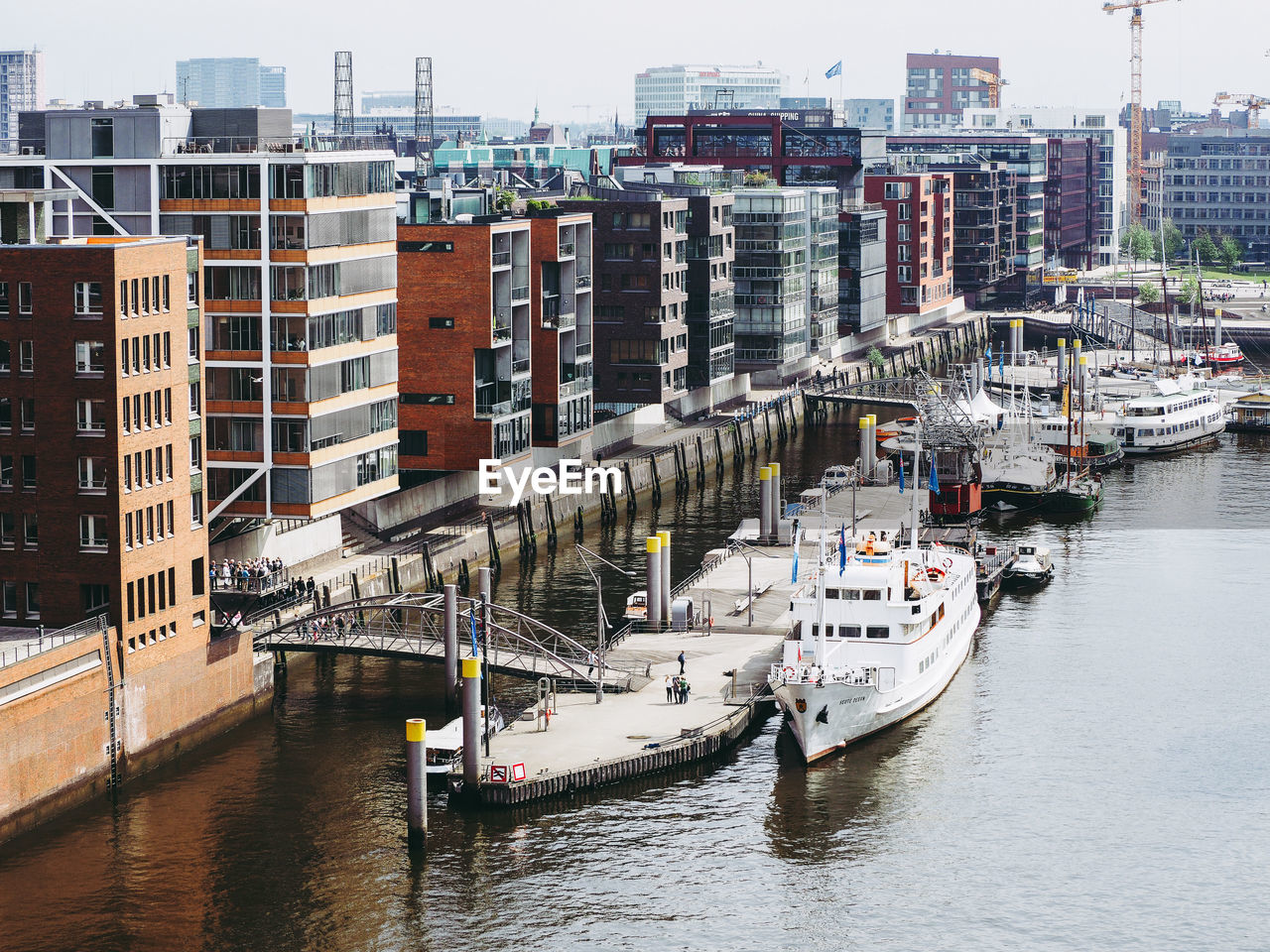 High angle view of boats moored at harbor by buildings in city against sky