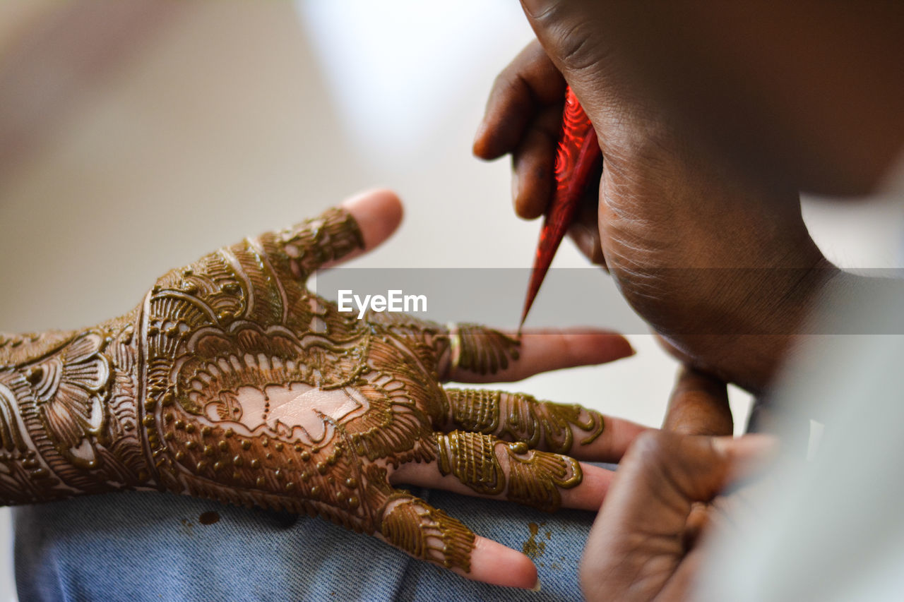 Cropped image of artist applying henna tattoo on woman hand