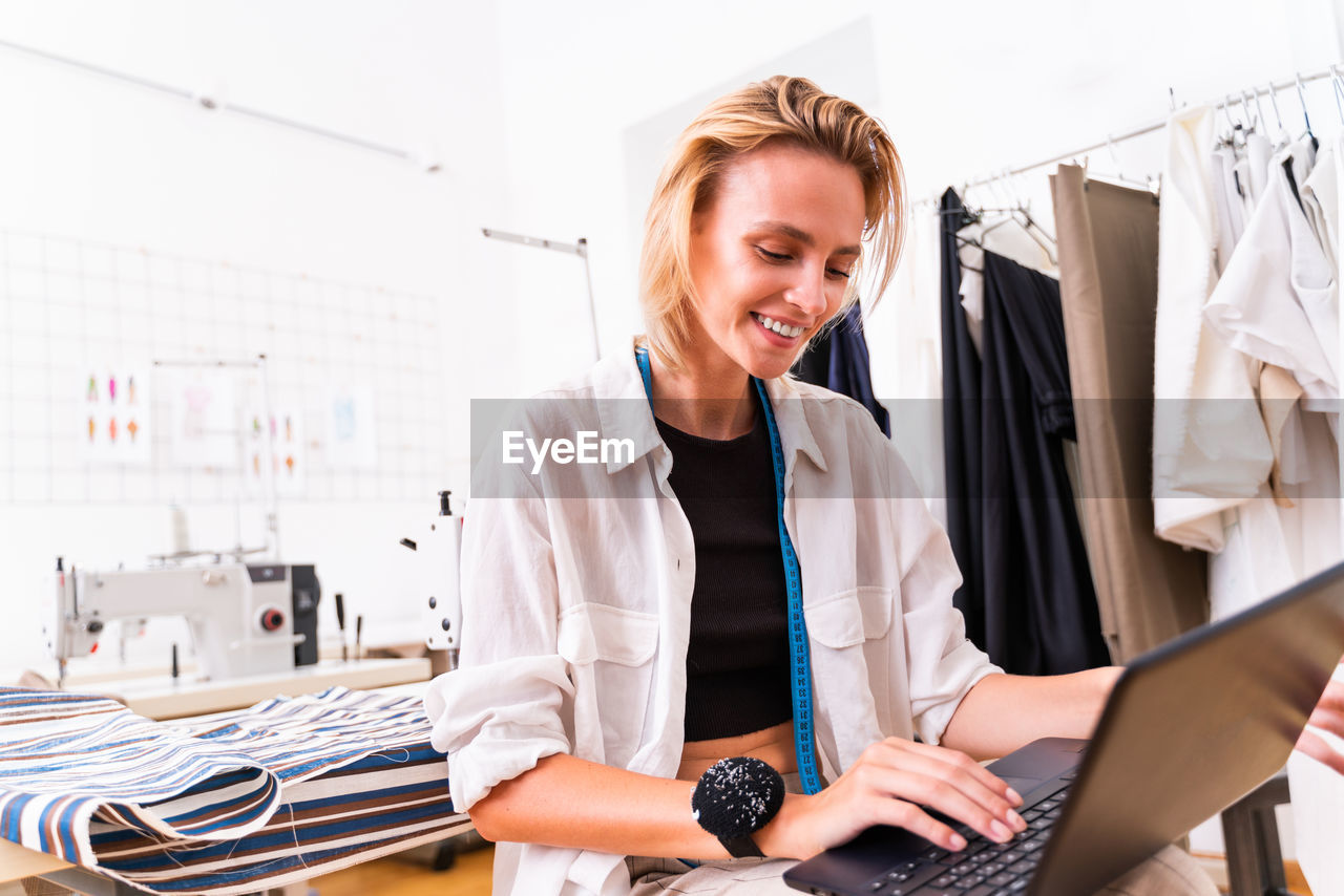 Smiling female designer using laptop at studio