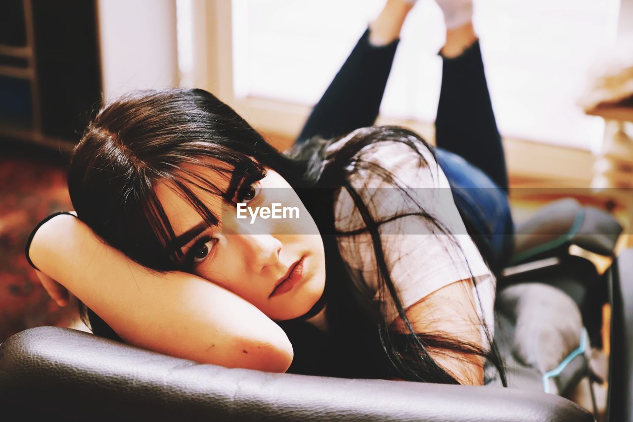 Portrait of teenage girl lying on chair at home