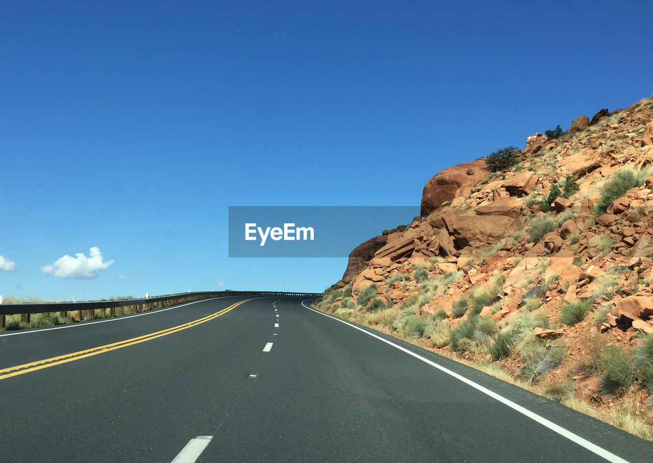 EMPTY ROAD ALONG LANDSCAPE AND BLUE SKY