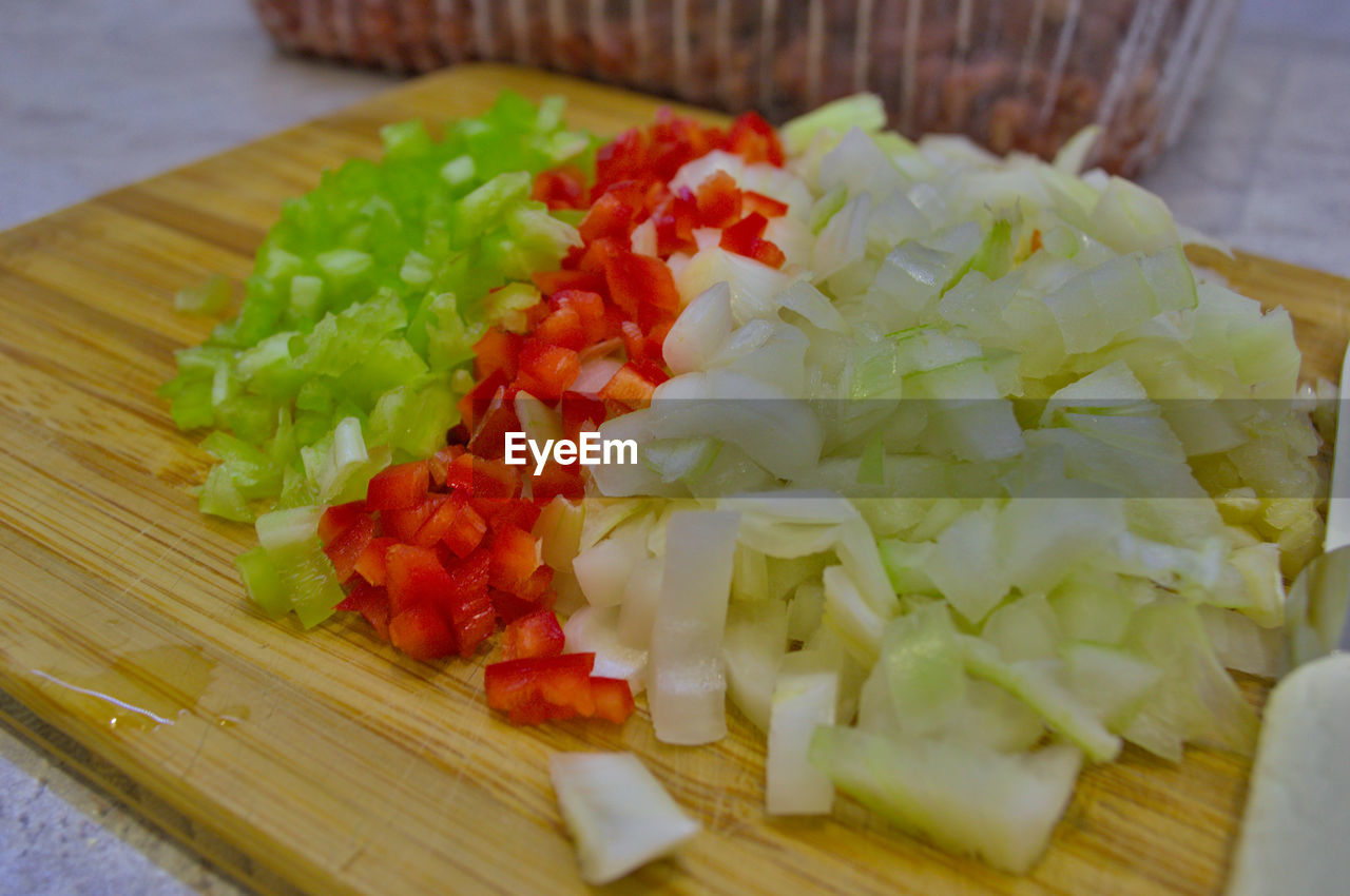 CLOSE-UP OF CHOPPED VEGETABLES ON CUTTING BOARD ON TABLE