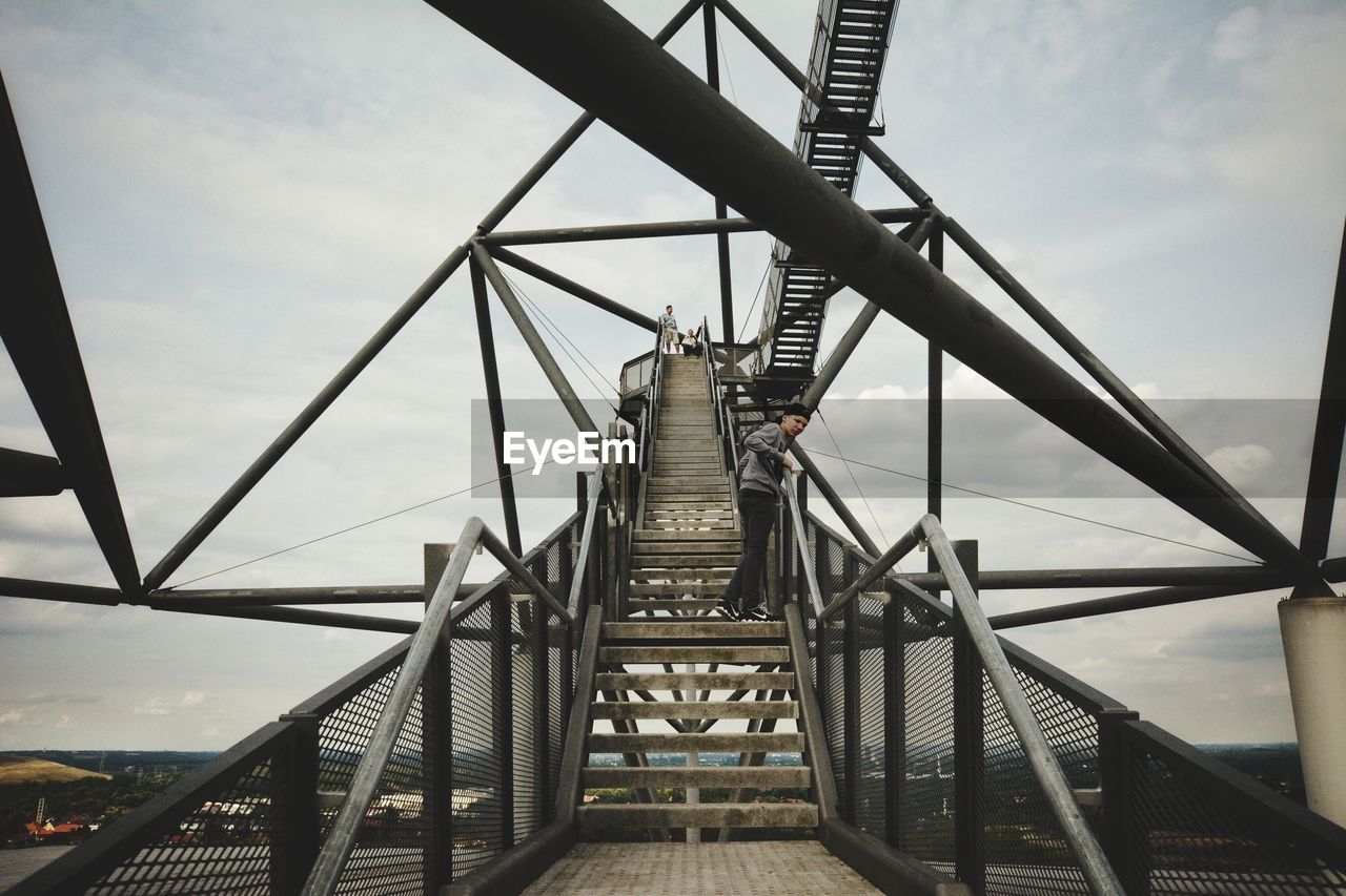Low angle view of boy standing bridge staircase