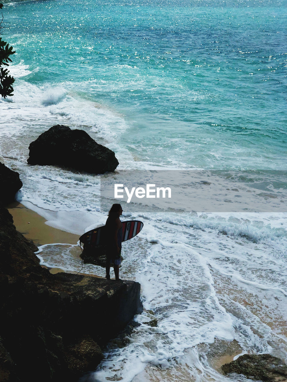 REAR VIEW OF WOMAN LOOKING AT SEA SHORE