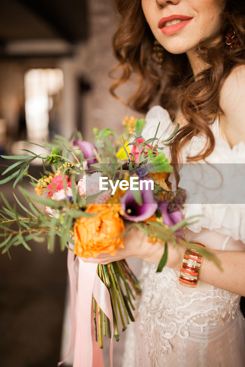 Redhead bride in dress holding wedding bouquet and smiling. wedding day concept