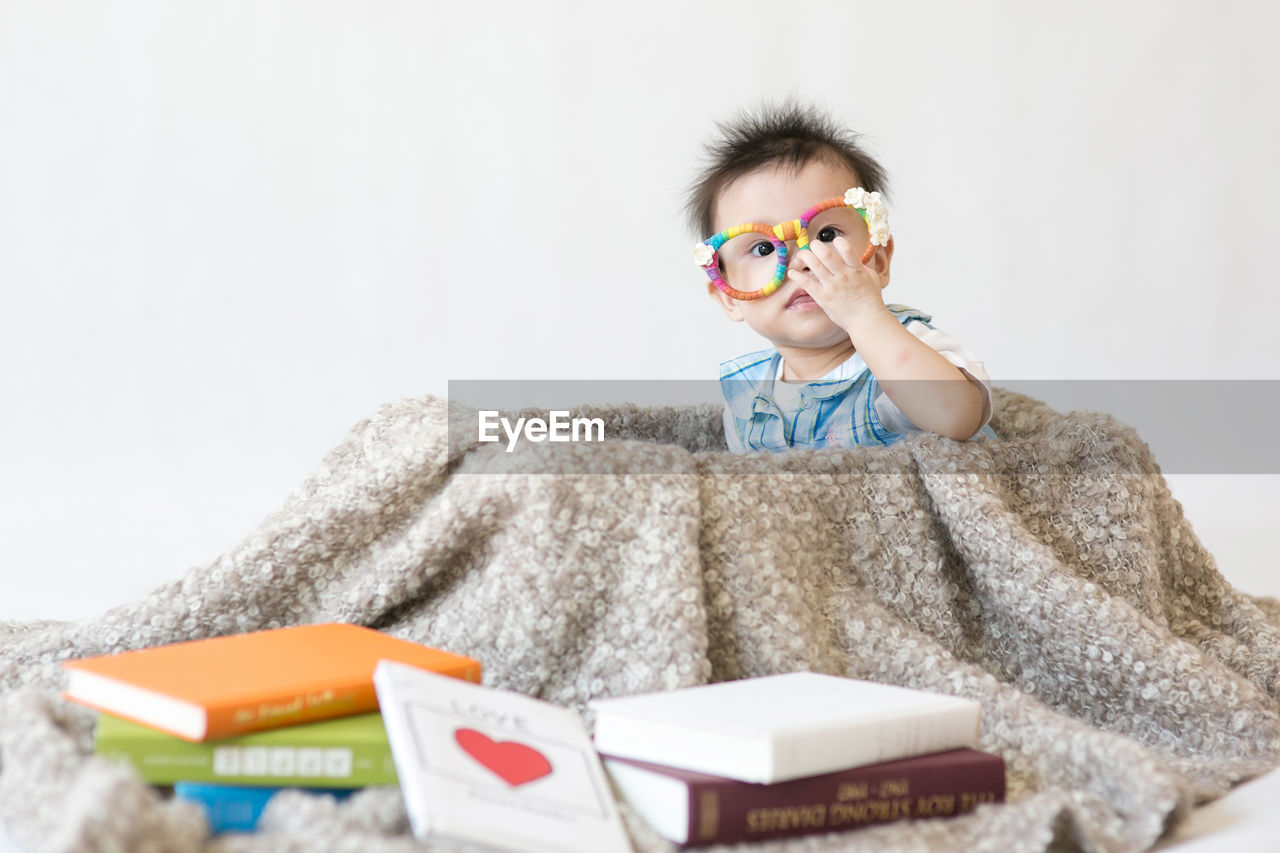 Portrait of cute boy sitting by books at home