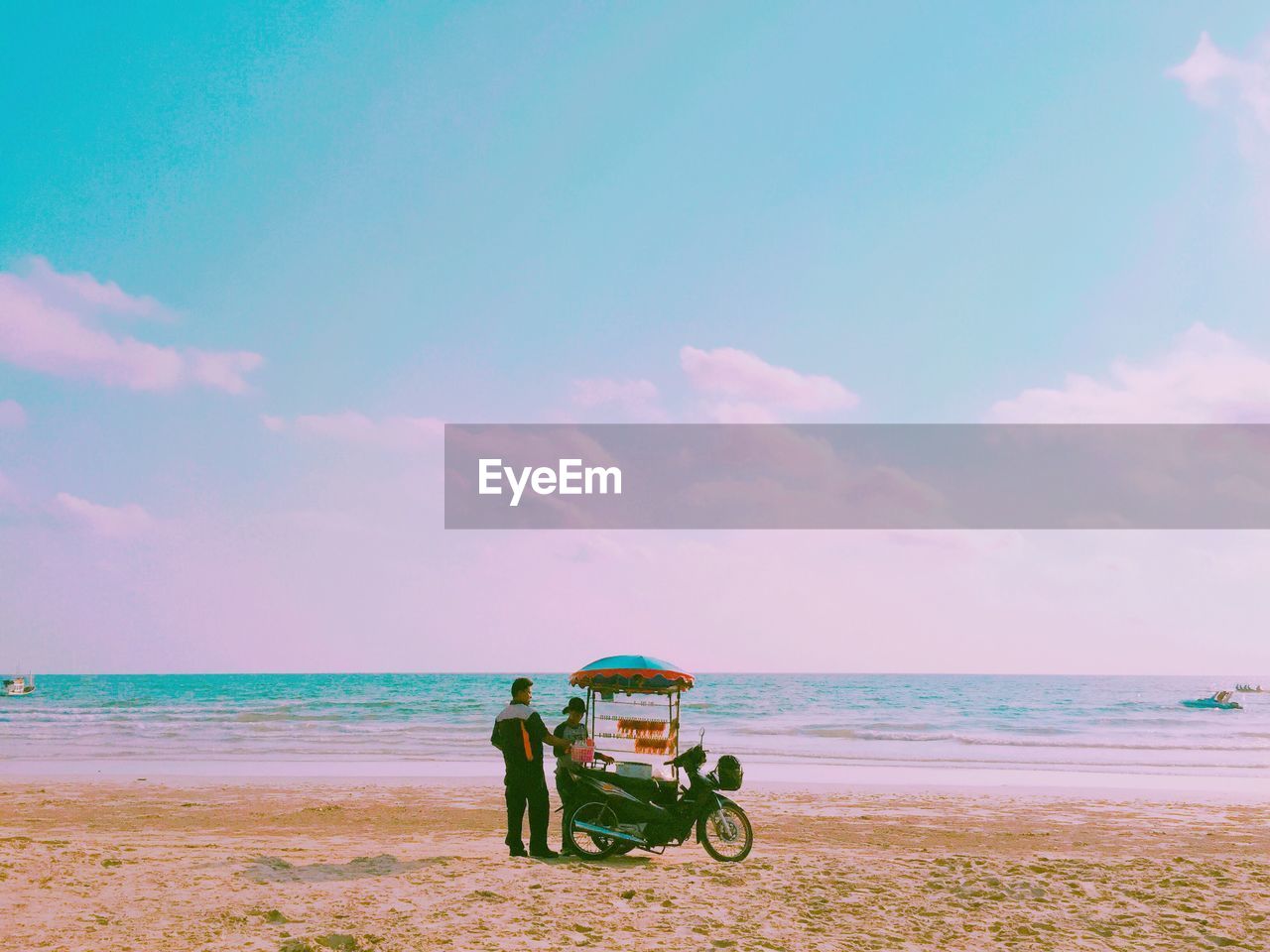 Man standing by woman selling food at beach