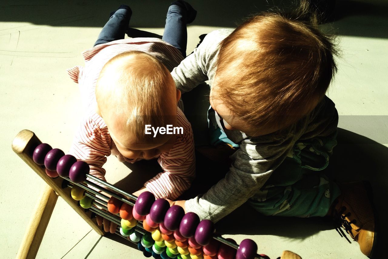 Siblings playing with abacus in home