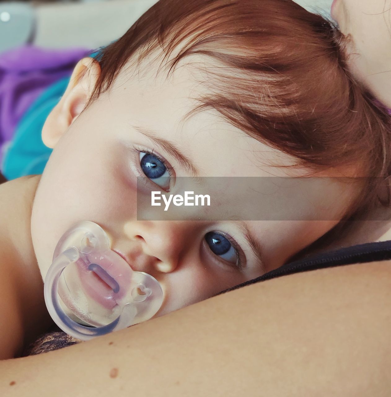 Close-up portrait of cute boy sucking pacifier at home