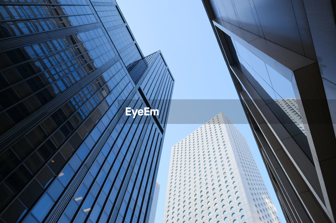 LOW ANGLE VIEW OF MODERN GLASS BUILDING AGAINST SKY