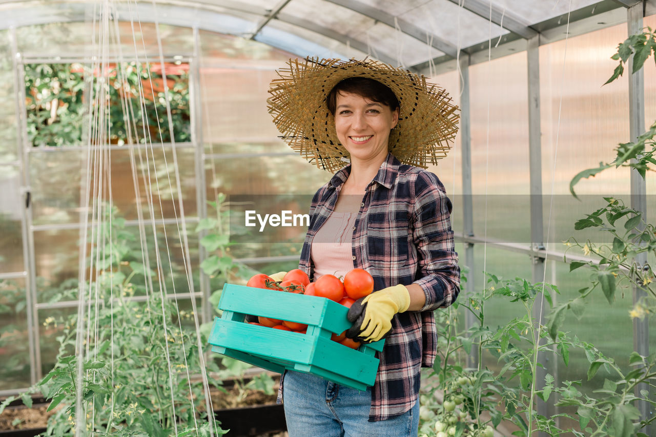 portrait of young woman wearing hat standing by plants