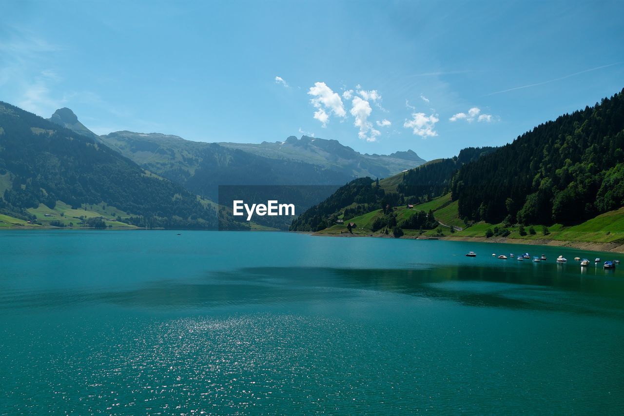 Scenic view of lake by mountains against sky