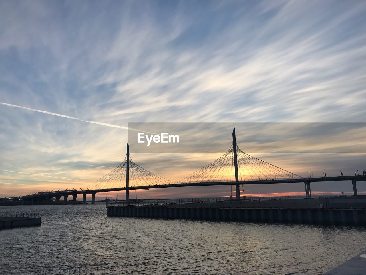 Suspension bridge over sea against sky during sunset