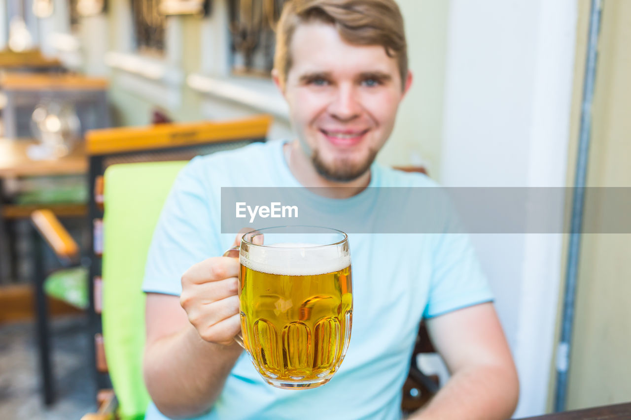 PORTRAIT OF YOUNG MAN DRINKING GLASS