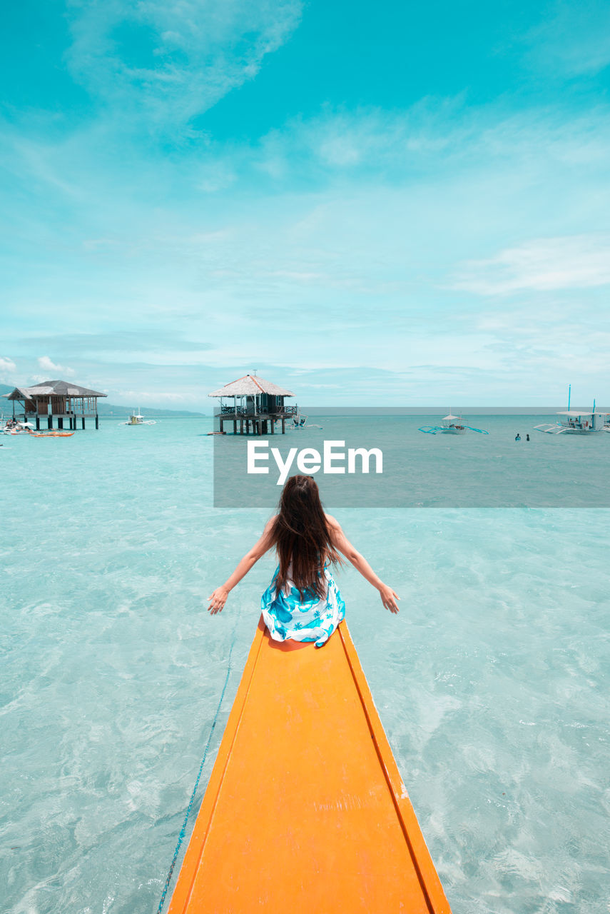 Rear view of woman sitting in boat on sea