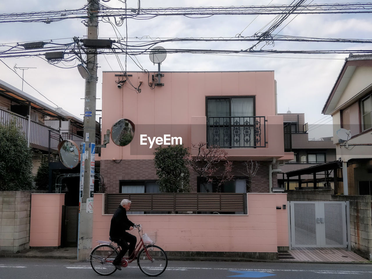 MAN RIDING BICYCLE ON STREET AGAINST BUILDINGS