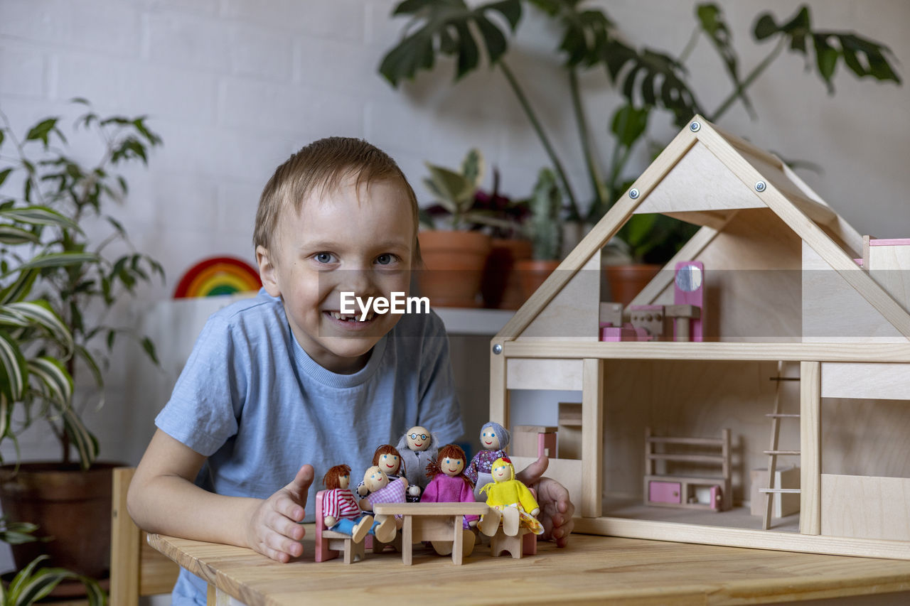 Portrait of boy sitting by house model at home