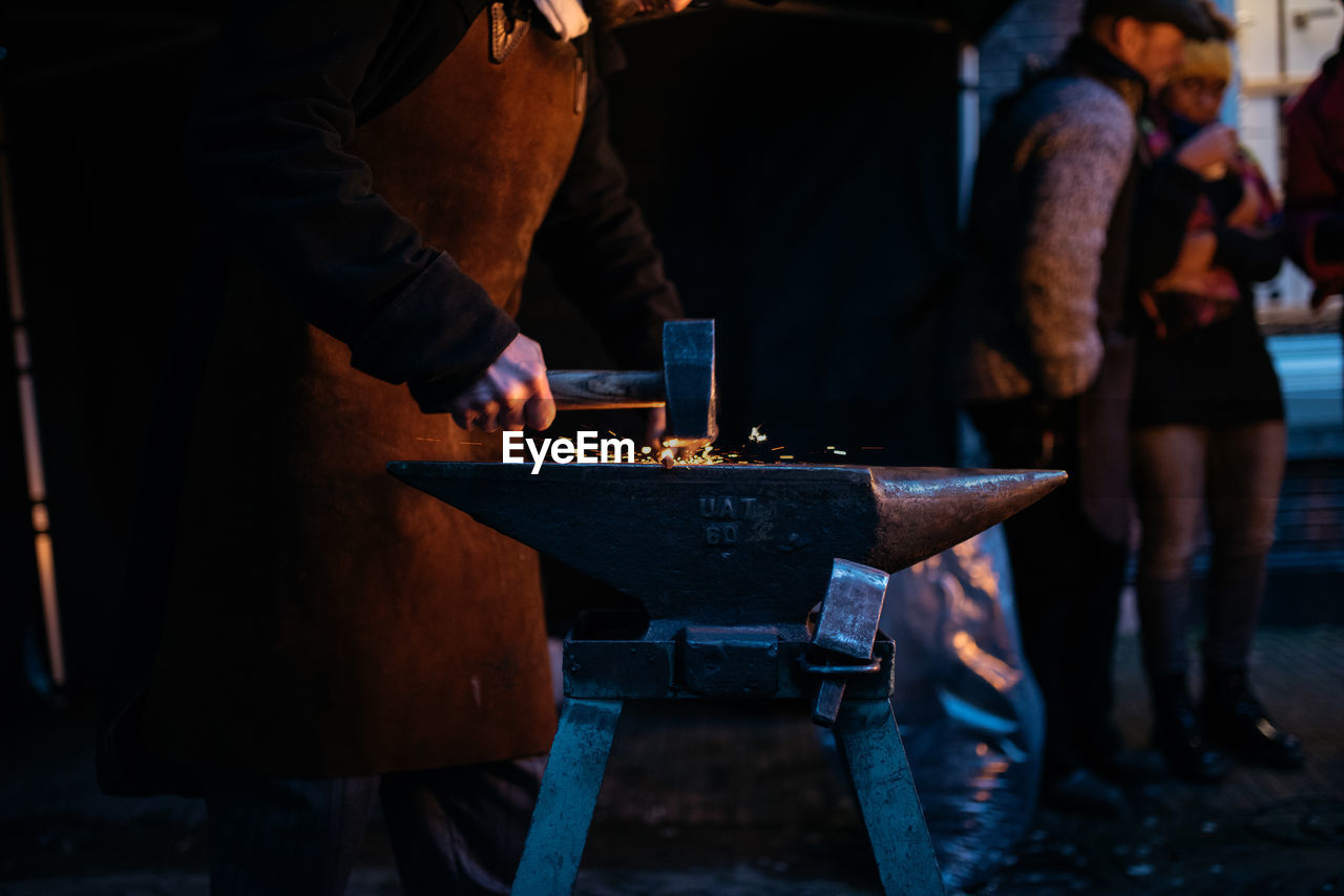 Midsection of blacksmith working at night