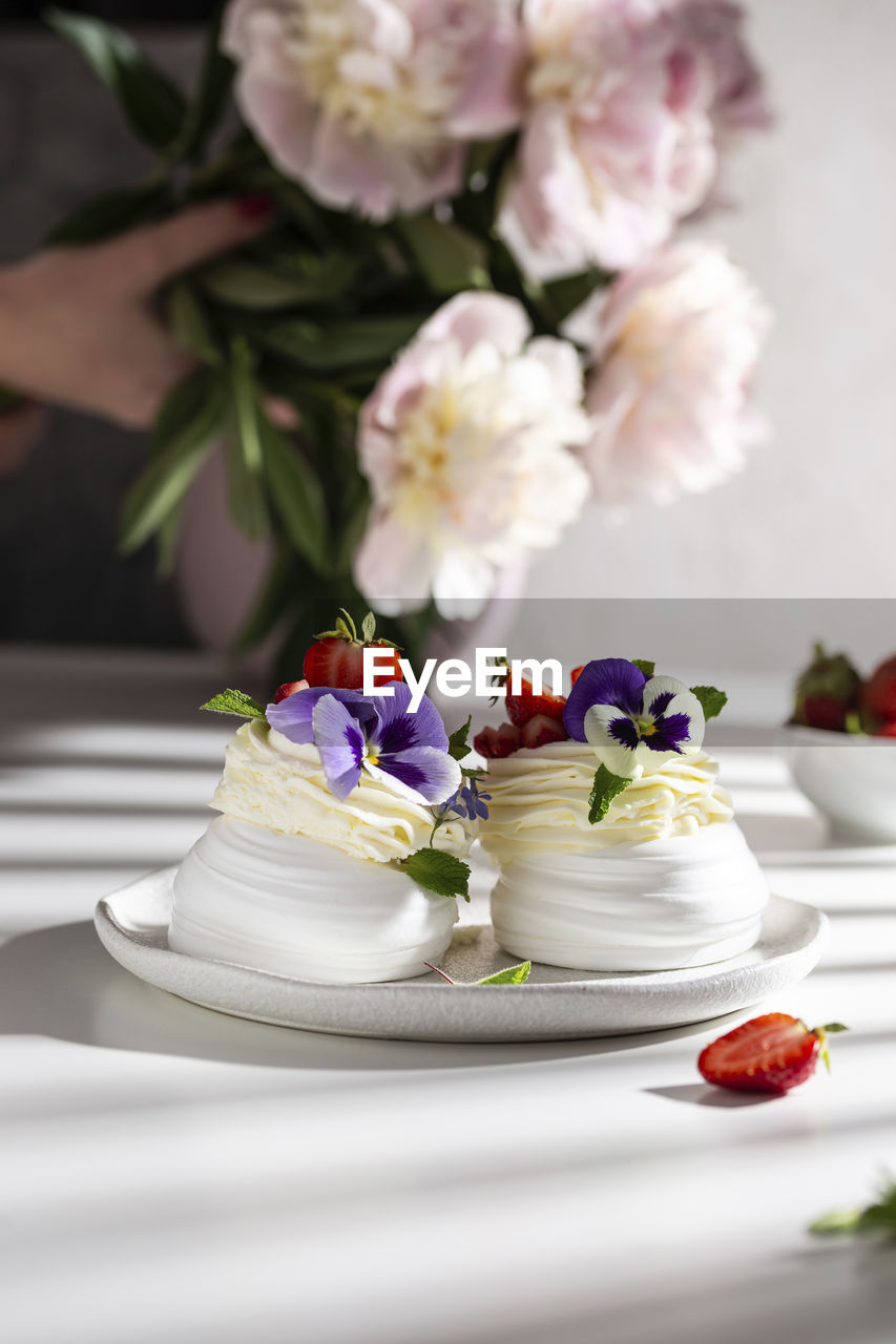 Sweet pavlova's dessert decorated with fresh strawberry and flowers