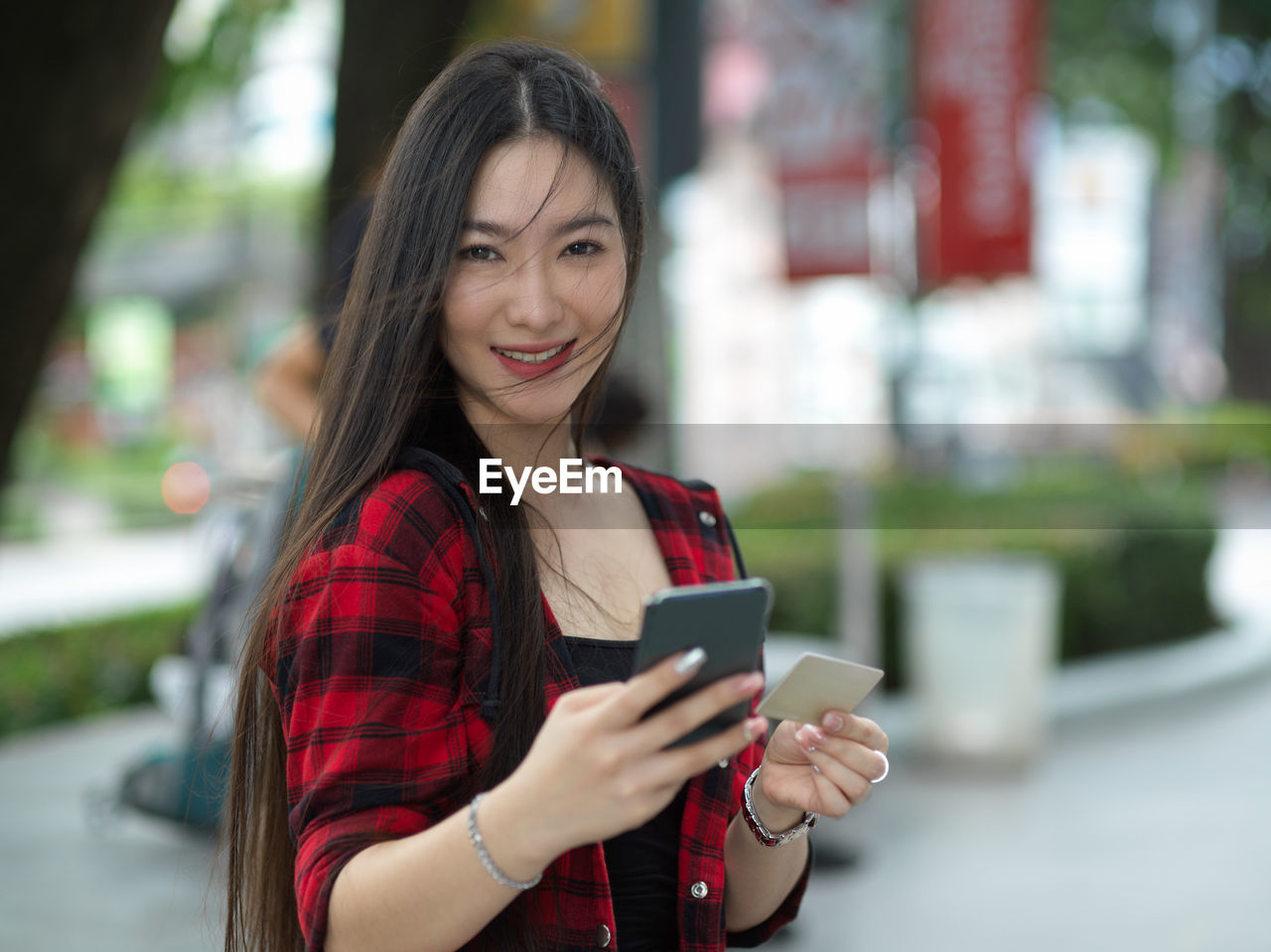 SMILING YOUNG WOMAN USING MOBILE PHONE