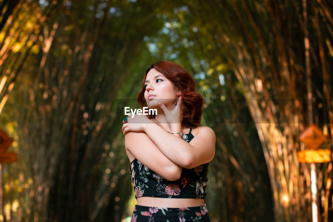 PORTRAIT OF YOUNG WOMAN STANDING OUTDOORS