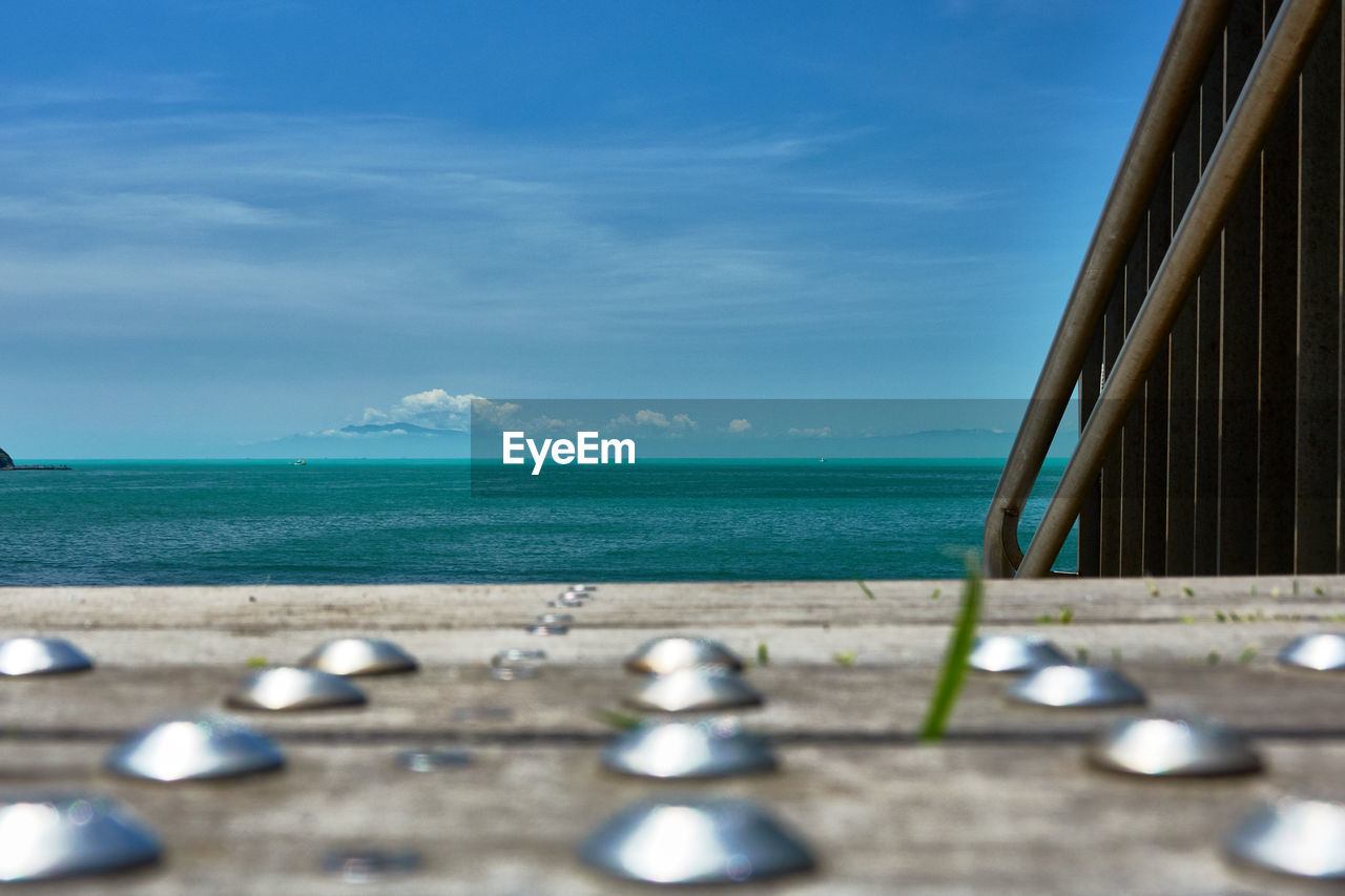 Scenic view of sea against sky with close up of  wooden deck 