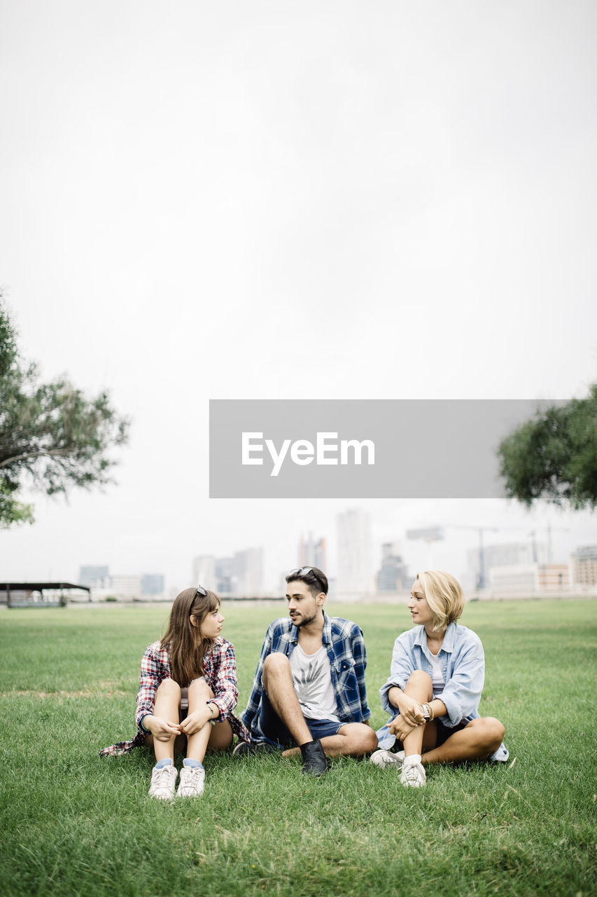 Friends sitting on grassy field