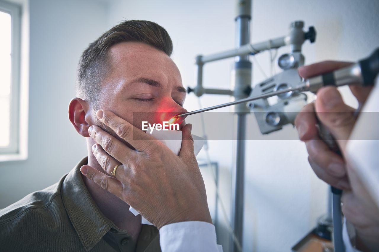 Cropped hand of doctor examining patients nose