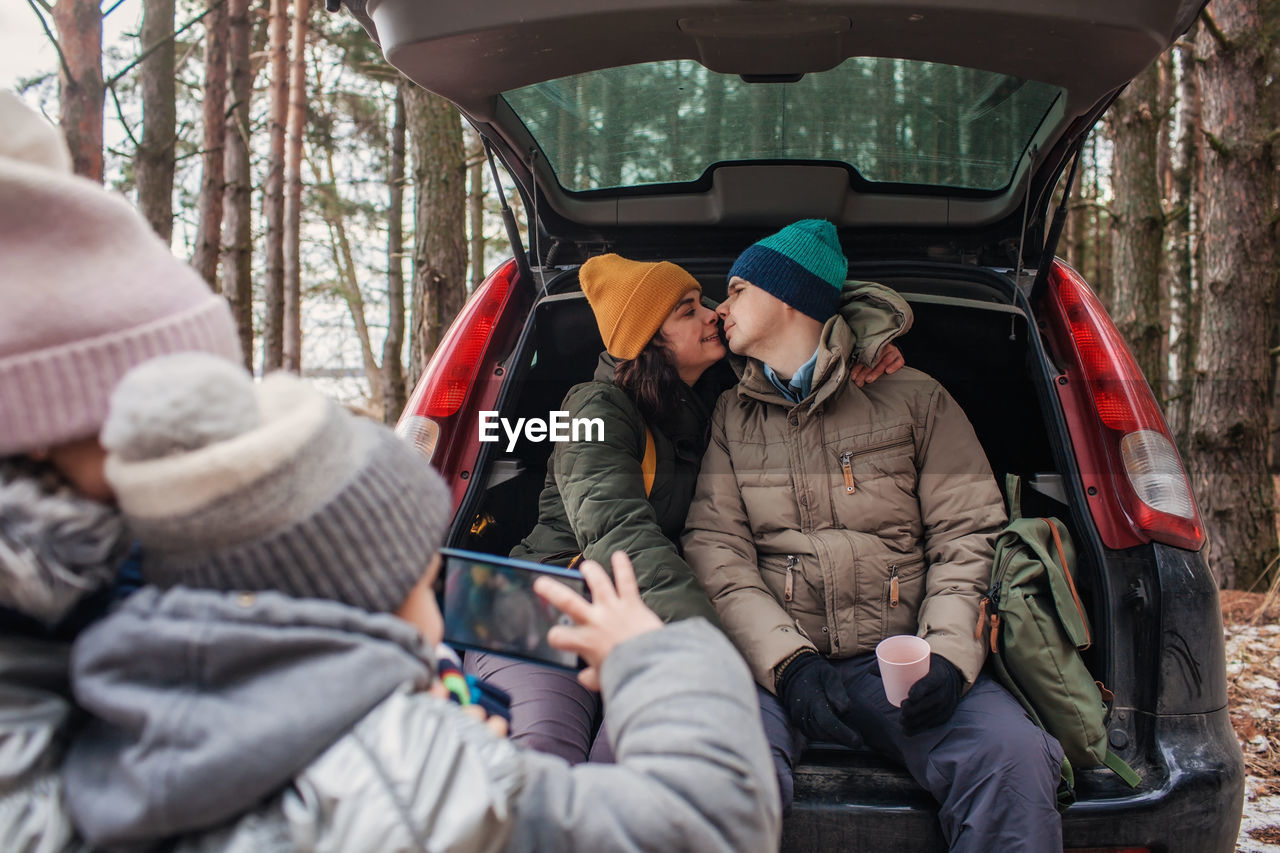 Winter family road trip. happy parents with kids make photo in the trunk of car