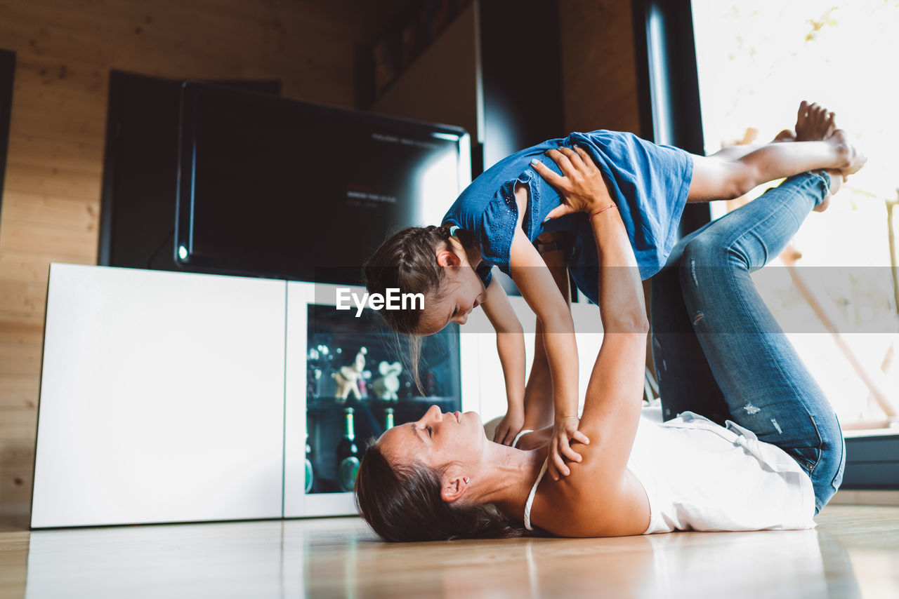 side view of boy playing with toy while lying on floor at home
