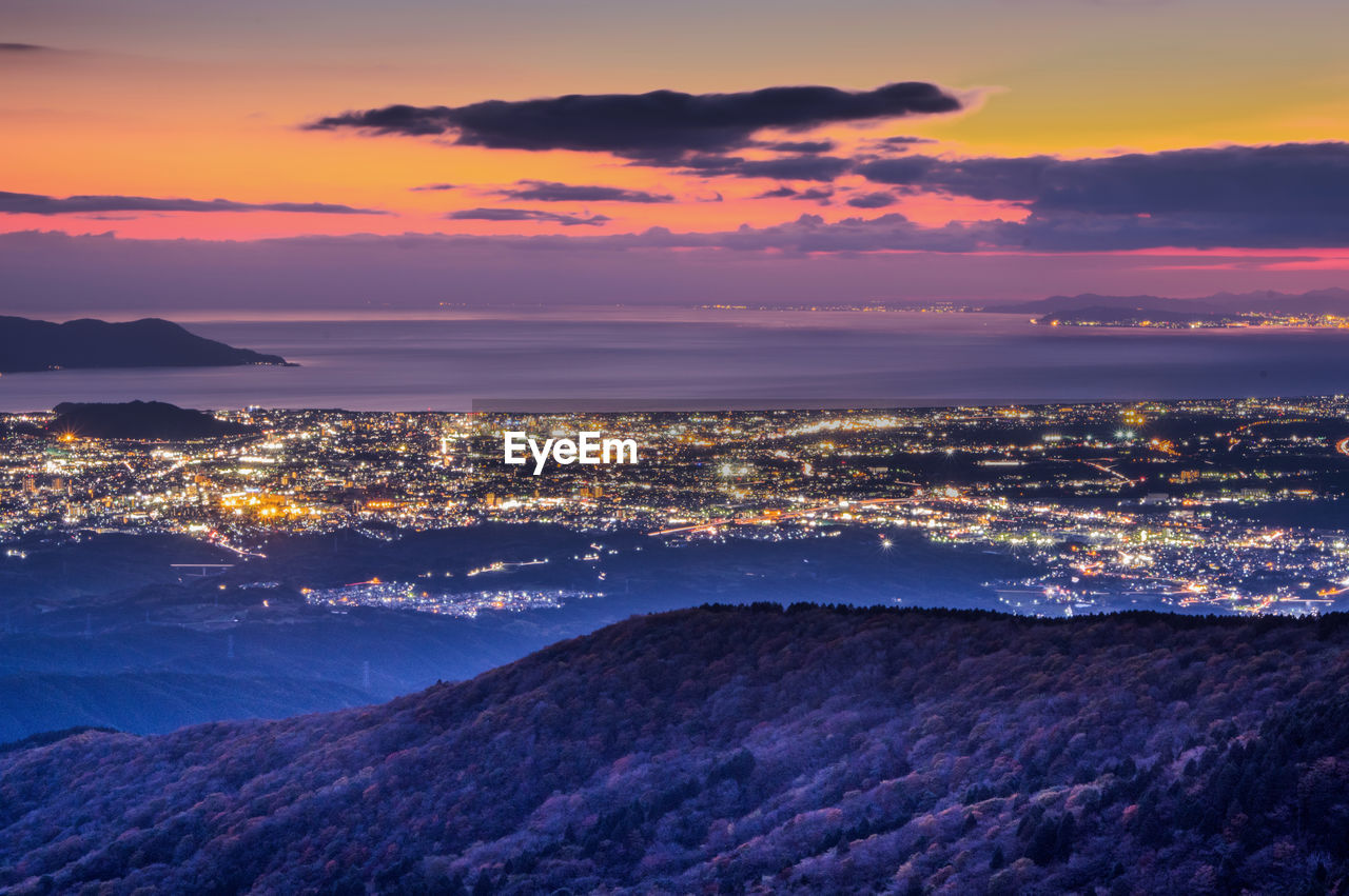 Aerial view of sea and cityscape against sky during sunset