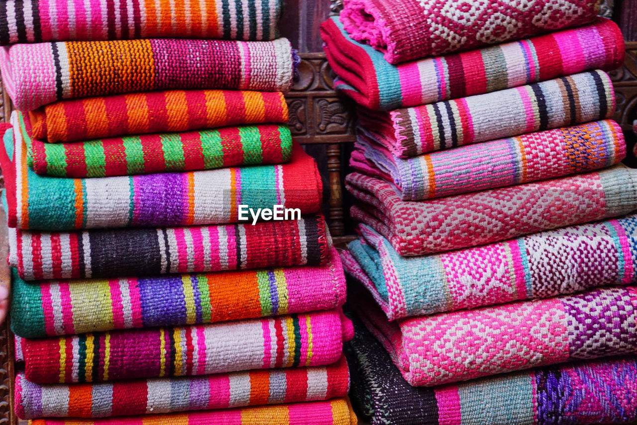 Two heaps of multi coloured traditional peruvian woven textiles at a street market, peru