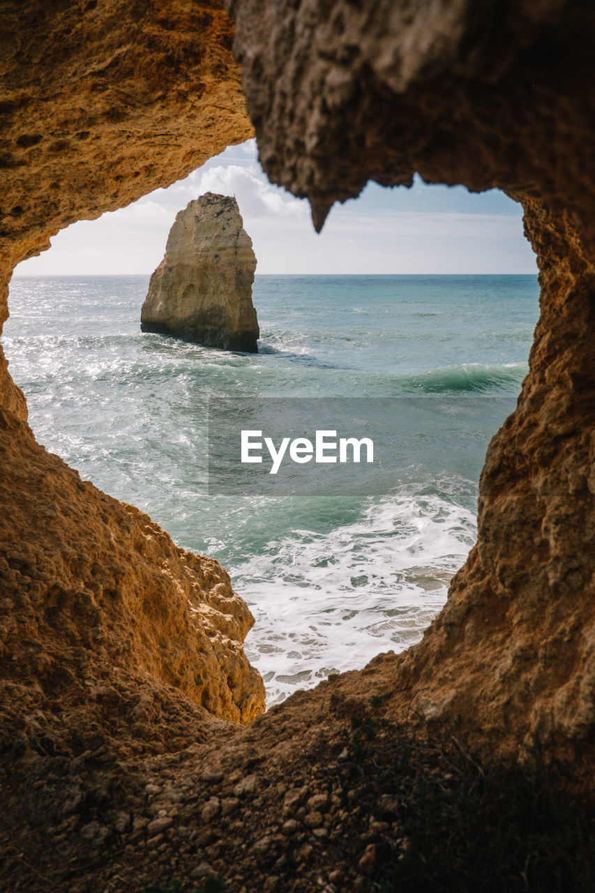 Scenic view of sea seen through rock formation against sky